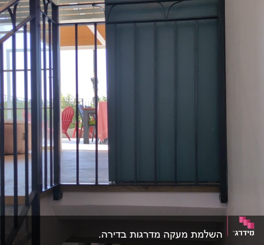 מעקה מתכת במבנה פנימי עם דלת פתוחה